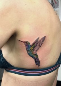 Colourful realistic hummingbird ribs tattoo by Davide -